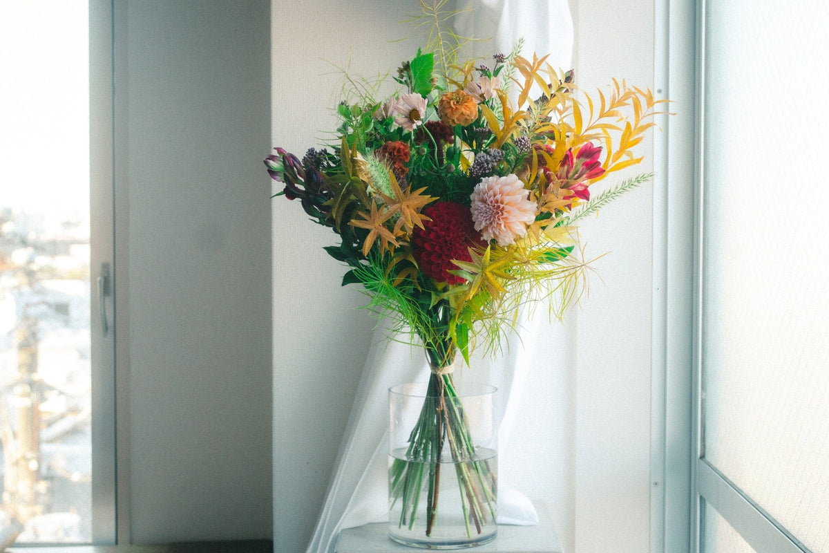 淡い色のダリアと秋色の葉を組み合わせた参加者の花束