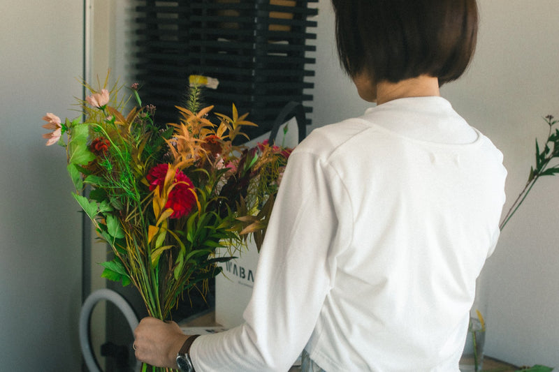秋の花の重なりを見ながら、手の中で花束を整える参加者